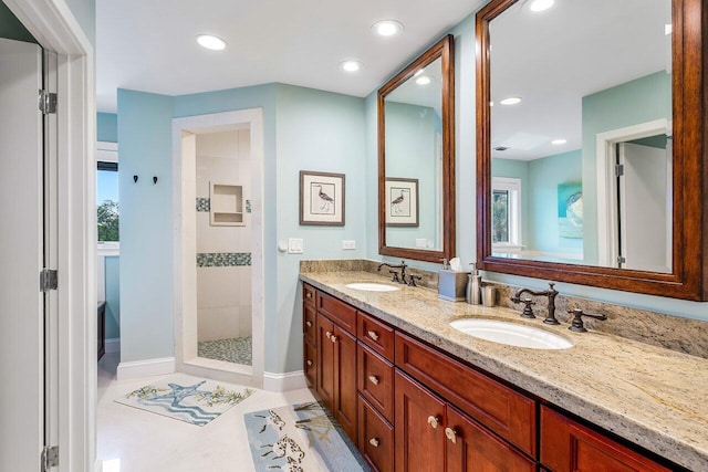 bathroom with tile flooring, tiled shower, double sink, and large vanity