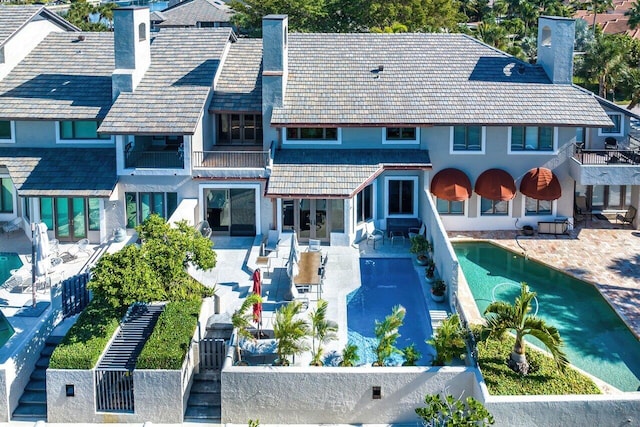 back of house featuring a pool, a balcony, and a patio