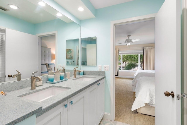 bathroom with ceiling fan, vanity with extensive cabinet space, and double sink