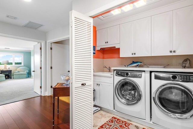 laundry room featuring light hardwood / wood-style floors, washing machine and dryer, cabinets, and sink