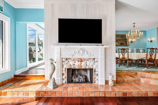 living room with a fireplace, an inviting chandelier, hardwood / wood-style flooring, and ornamental molding