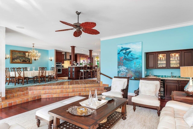 living room featuring ceiling fan with notable chandelier, light hardwood / wood-style flooring, ornate columns, and crown molding