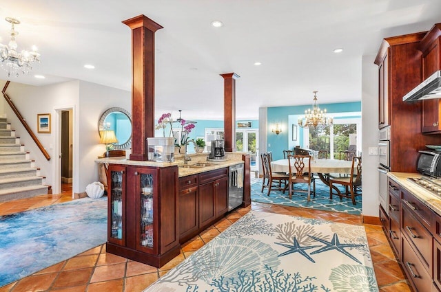 kitchen with light tile flooring, gas stovetop, hanging light fixtures, decorative columns, and a chandelier