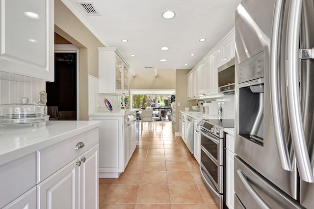 kitchen with stainless steel appliances, crown molding, light tile flooring, white cabinets, and sink