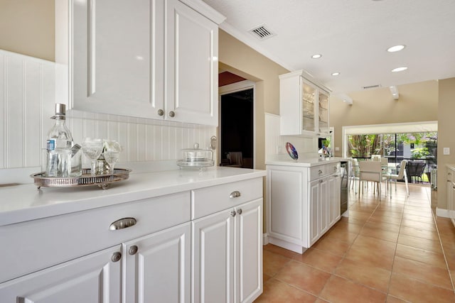 kitchen with vaulted ceiling, white cabinetry, and light tile floors