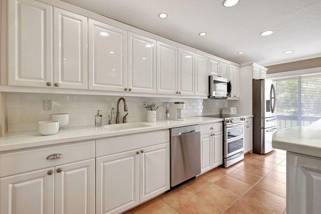 kitchen with appliances with stainless steel finishes, sink, tasteful backsplash, white cabinetry, and light tile flooring