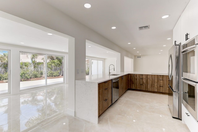 kitchen featuring white cabinets, sink, kitchen peninsula, and stainless steel appliances