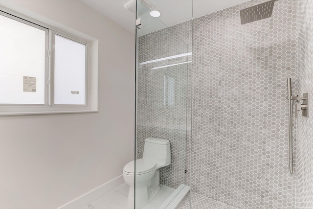 bathroom featuring a tile shower and toilet