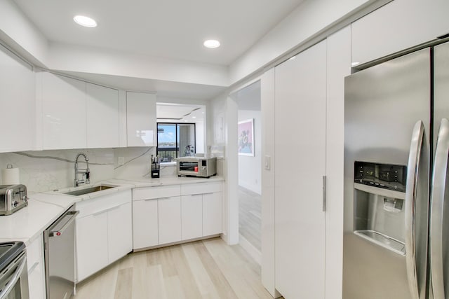 kitchen featuring light hardwood / wood-style flooring, stainless steel appliances, white cabinets, and sink