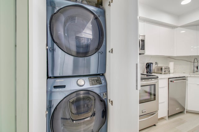 washroom featuring stacked washer / dryer, light hardwood / wood-style floors, and sink