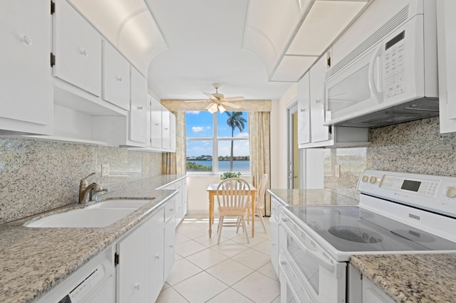 kitchen with a water view, white appliances, ceiling fan, sink, and light tile floors