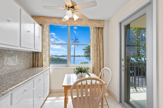 kitchen featuring a water view, white cabinetry, light tile floors, and tasteful backsplash