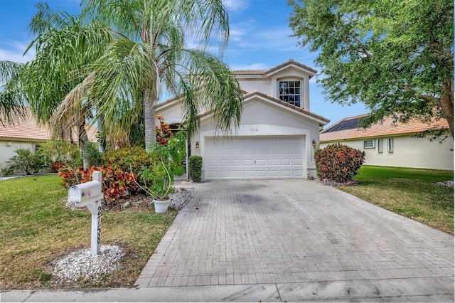 mediterranean / spanish home featuring a garage and a front lawn