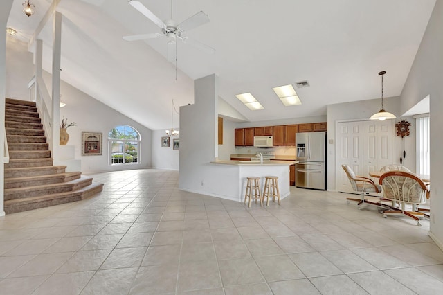 interior space with ceiling fan, light tile floors, high vaulted ceiling, stainless steel fridge with ice dispenser, and pendant lighting