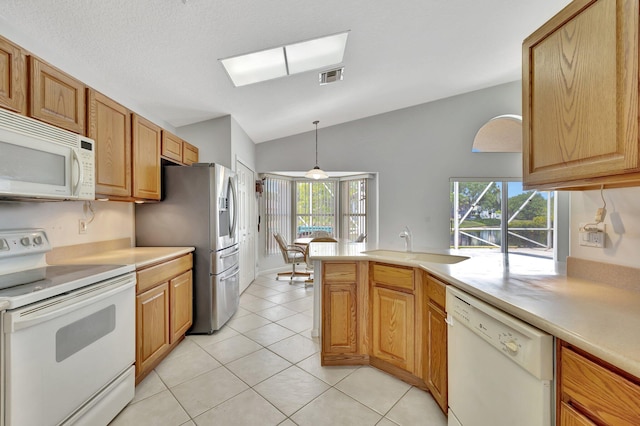 kitchen with white appliances, light tile flooring, sink, pendant lighting, and vaulted ceiling with skylight