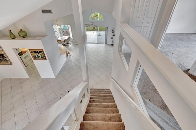 staircase with tile walls, high vaulted ceiling, and carpet flooring