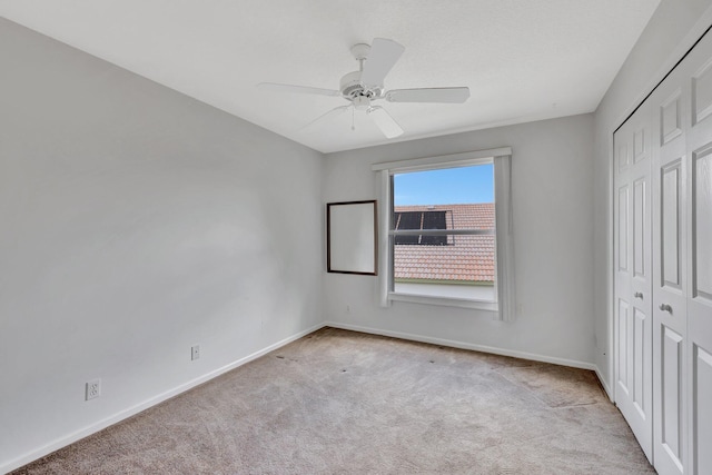 unfurnished bedroom featuring light colored carpet, ceiling fan, and a closet