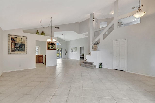 unfurnished living room with a towering ceiling, light tile floors, and an inviting chandelier