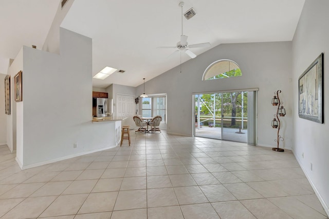 unfurnished living room with high vaulted ceiling, ceiling fan, and light tile floors