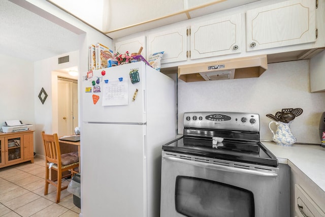 kitchen with wall chimney exhaust hood, stainless steel electric range, white cabinetry, white fridge, and light tile floors