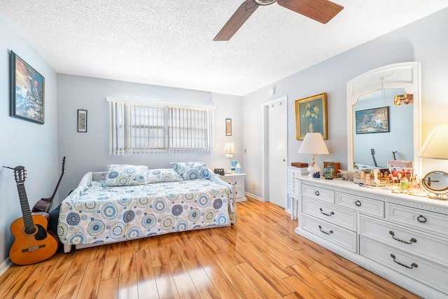 bedroom featuring light hardwood / wood-style flooring, ceiling fan, and a textured ceiling