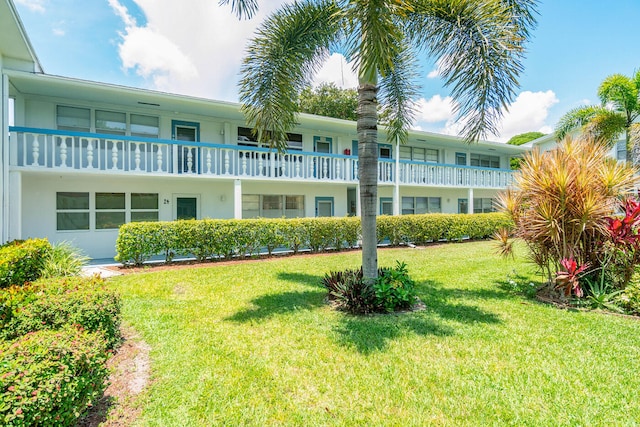 rear view of property with a balcony and a lawn