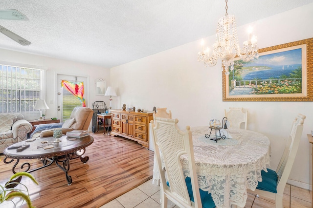 tiled dining space with ceiling fan with notable chandelier and a textured ceiling