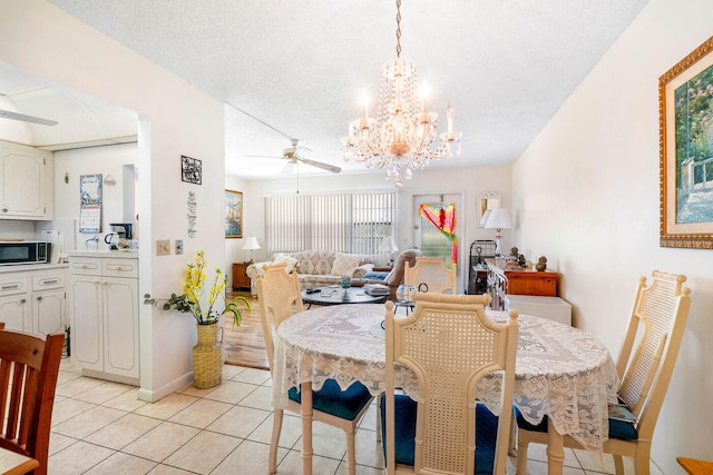 dining space with ceiling fan with notable chandelier, a textured ceiling, and light tile floors