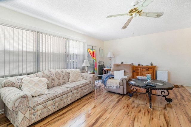 living room with light hardwood / wood-style floors, ceiling fan, and a textured ceiling