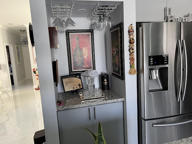 kitchen with stainless steel fridge, stone counters, marble finish floor, and crown molding
