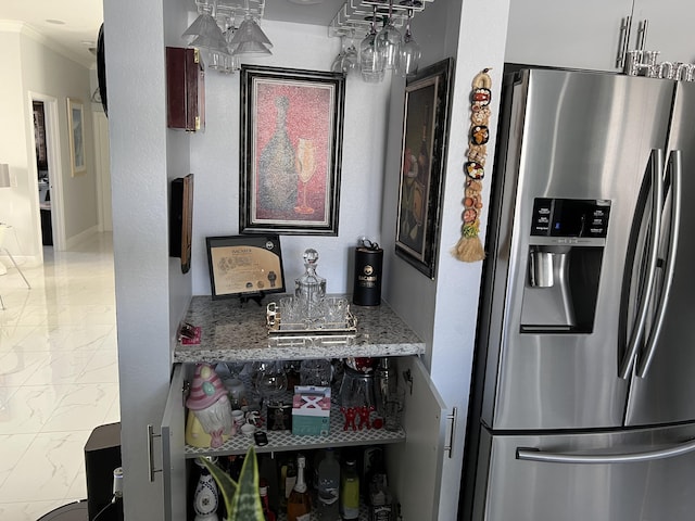 kitchen with light stone countertops, stainless steel fridge, and ornamental molding