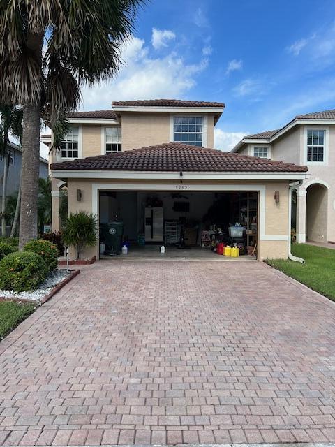 view of front of home with stucco siding, a tile roof, decorative driveway, and a garage