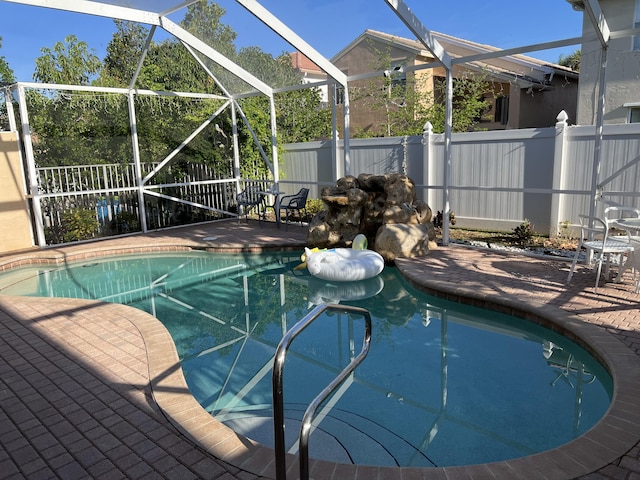 view of swimming pool with glass enclosure, a fenced in pool, a patio area, and a fenced backyard