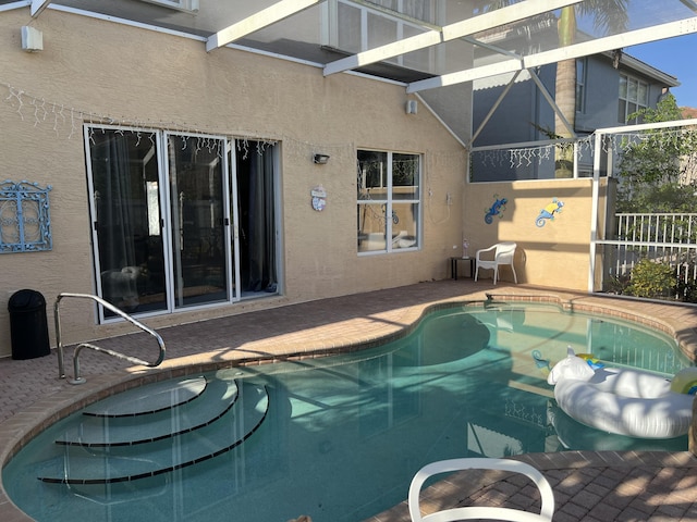 outdoor pool with fence, a patio area, and a lanai