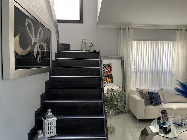 staircase with marble finish floor and a wealth of natural light