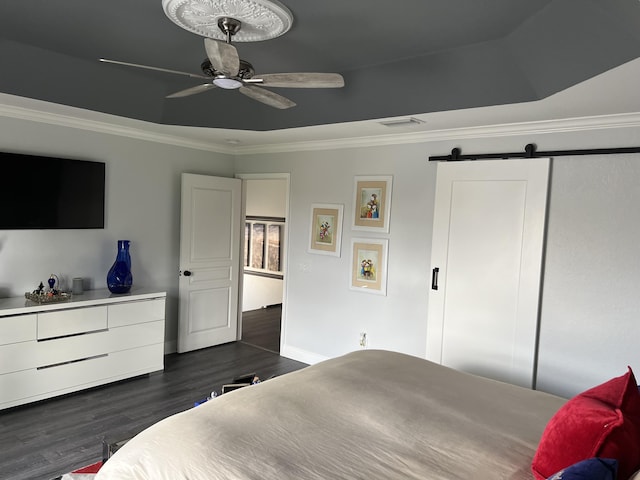 bedroom featuring dark wood finished floors, a barn door, baseboards, visible vents, and crown molding