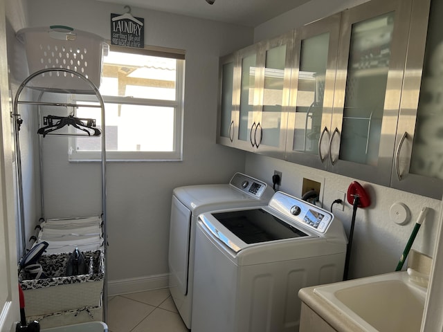 laundry area featuring washing machine and dryer, a sink, a wealth of natural light, and light tile patterned floors