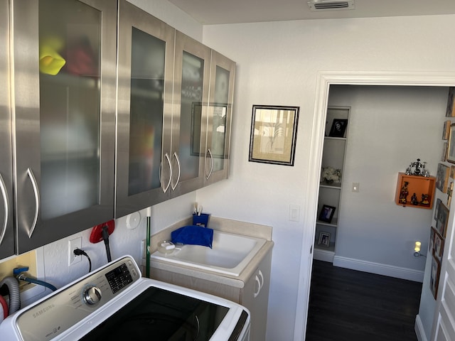 clothes washing area featuring visible vents, washer / dryer, baseboards, cabinet space, and dark wood-style flooring