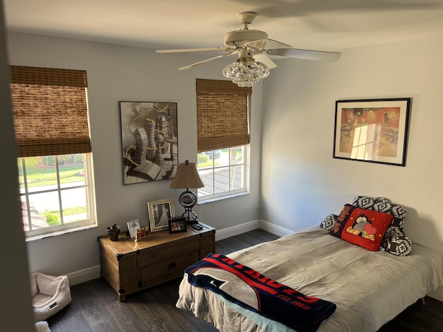 bedroom with dark wood finished floors, baseboards, and multiple windows