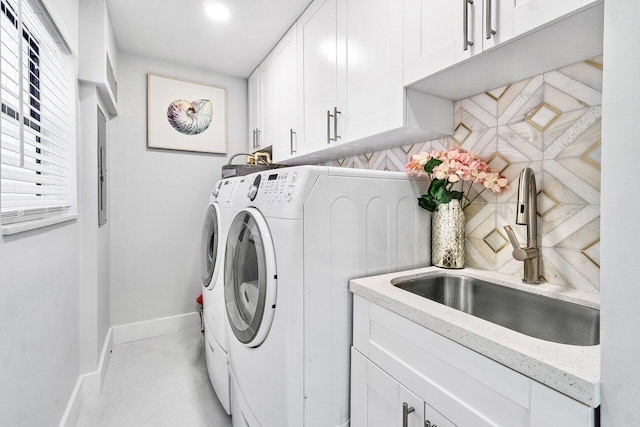 clothes washing area featuring washing machine and dryer, sink, and cabinets