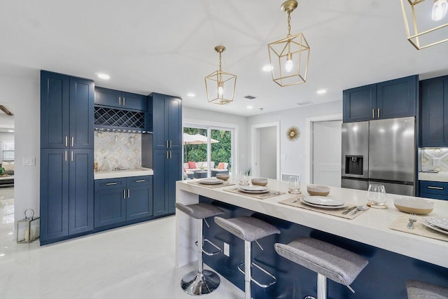 kitchen with a breakfast bar area, blue cabinetry, hanging light fixtures, and stainless steel fridge