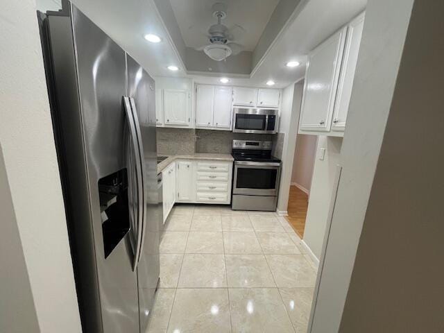 kitchen with white cabinets, a raised ceiling, light tile patterned floors, tasteful backsplash, and stainless steel appliances