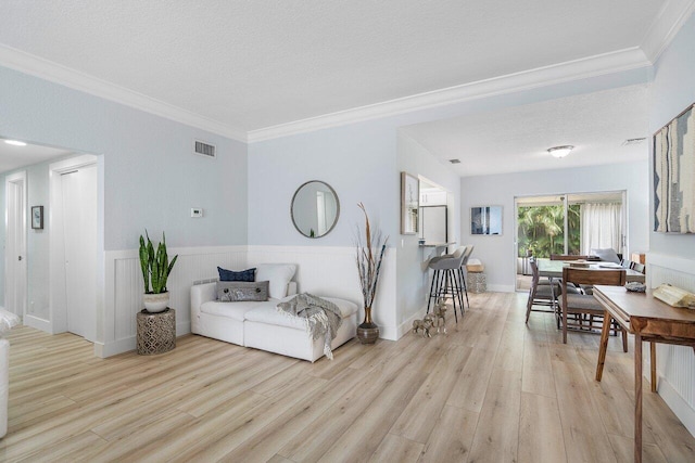 living room with light wood-type flooring, a textured ceiling, and ornamental molding