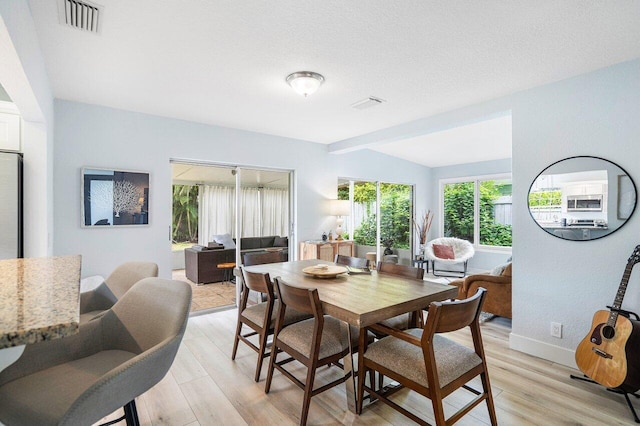 dining area with vaulted ceiling and light hardwood / wood-style floors