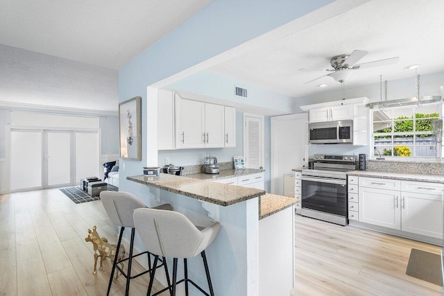 kitchen featuring light stone counters, ceiling fan, stainless steel appliances, and white cabinets