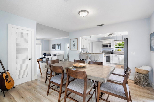 dining space featuring light wood-type flooring and a textured ceiling