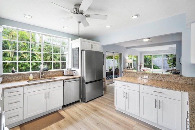 kitchen featuring light wood-type flooring, sink, white cabinets, appliances with stainless steel finishes, and ceiling fan