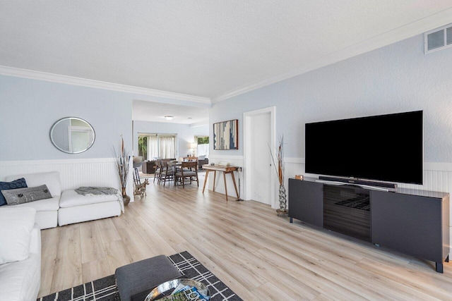 living room featuring a textured ceiling, light hardwood / wood-style flooring, and ornamental molding