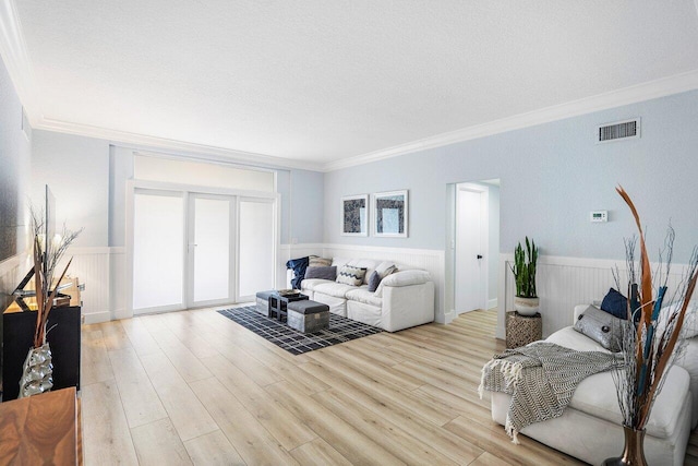 living room featuring ornamental molding, light wood-type flooring, and a textured ceiling