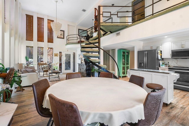 dining room featuring wood-type flooring and a towering ceiling